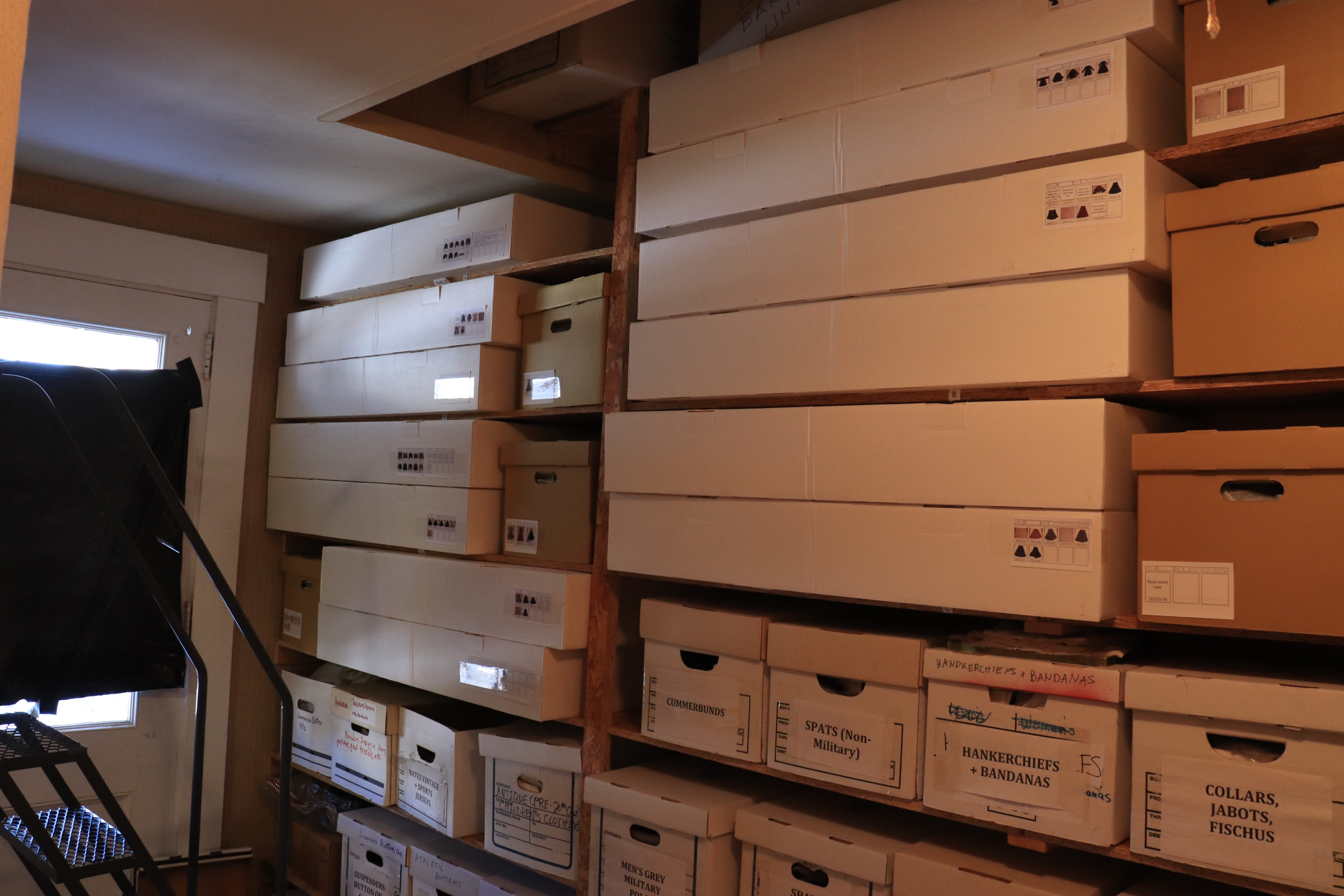 White archival boxes on wooden shelves in the Bates College Clothing Archive.