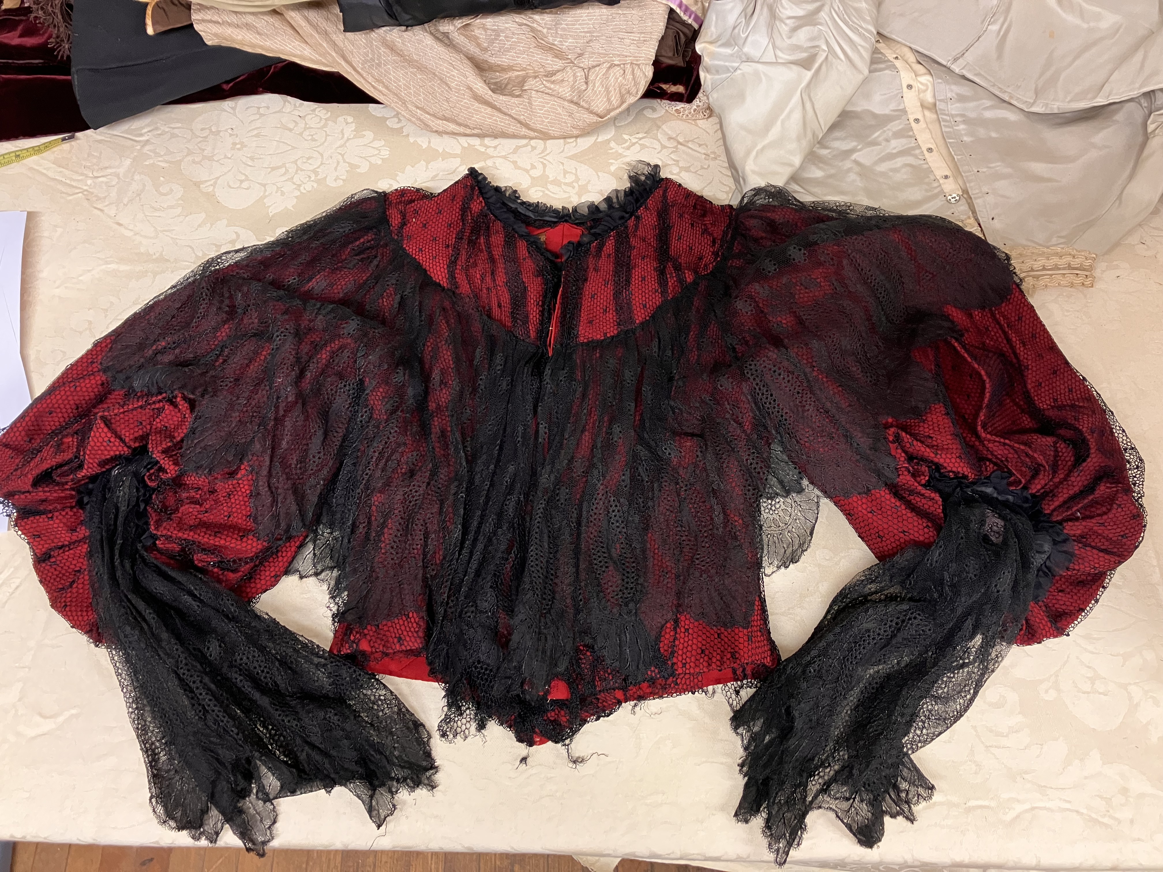 A red silk bodice from circa 1895 with black mesh and lace overlay.